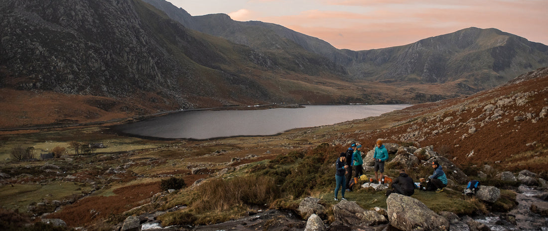 a group of friends hang out by a lake in the hills